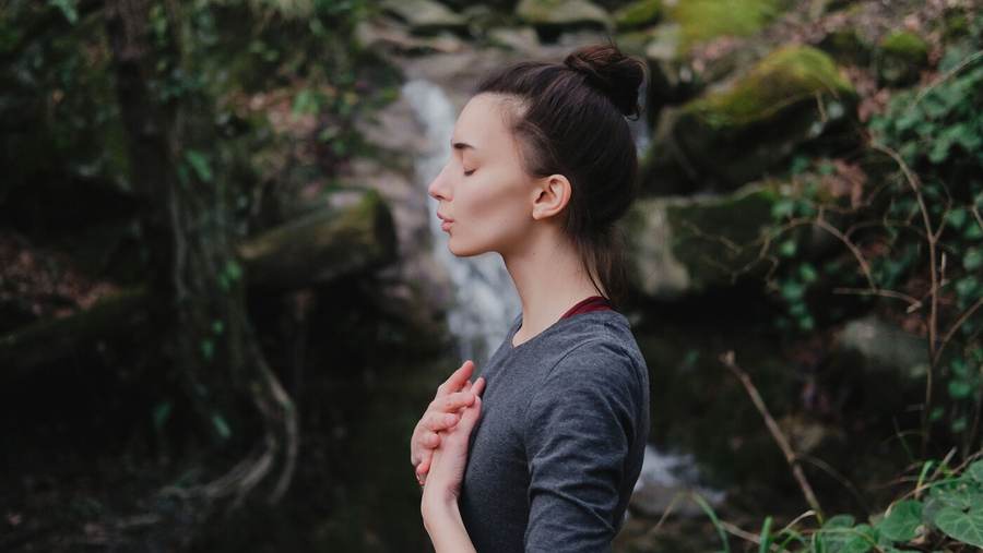 A person breathing out slowly in a green forest