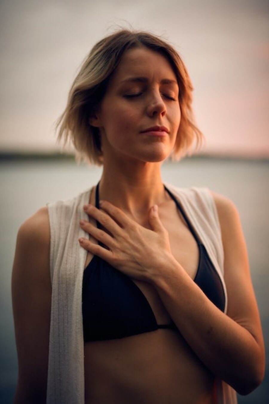A woman standing quietly with a hand over her heart