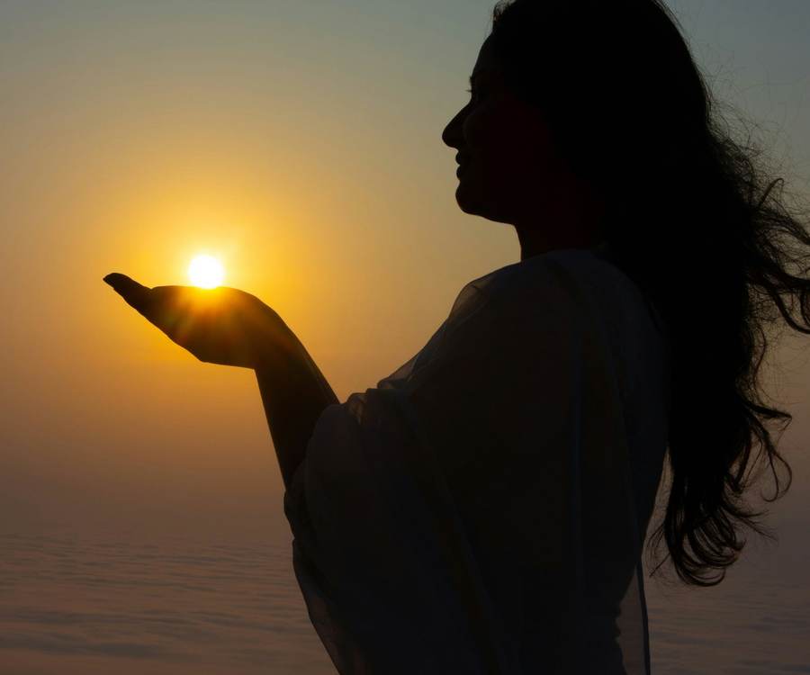 A woman holding the last of the sunlight in an open palm