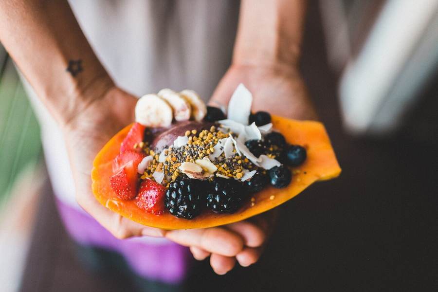 Hands holding a bowl of fresh fruit