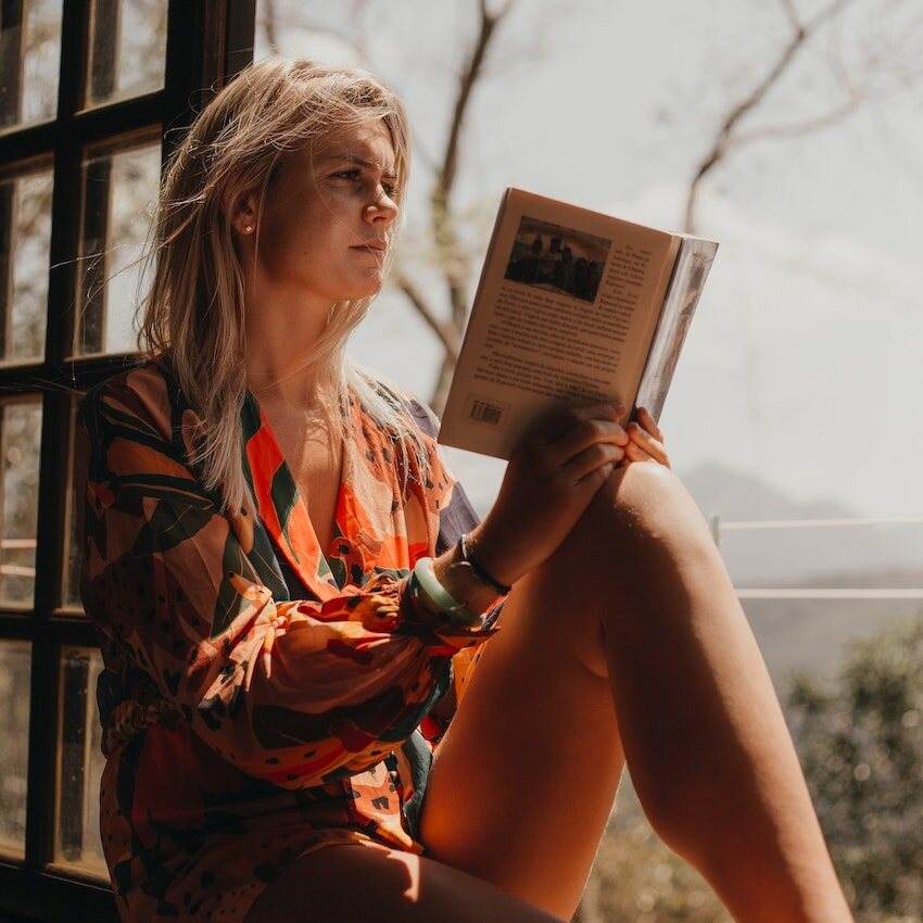 A person reading by a window in warm light