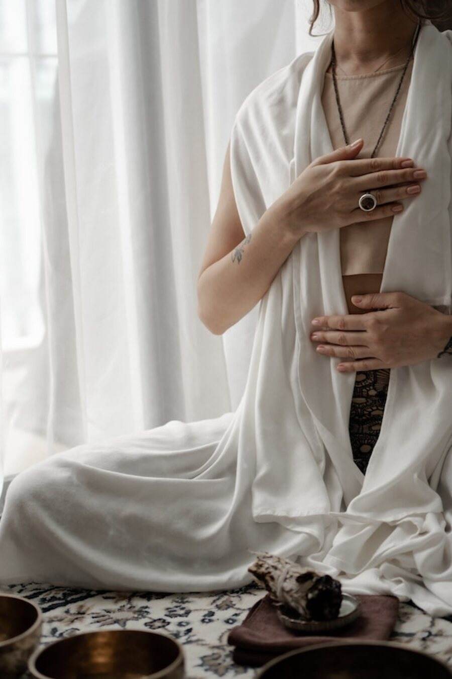 A woman sitting quietly in soft morning light, one hand over her heart