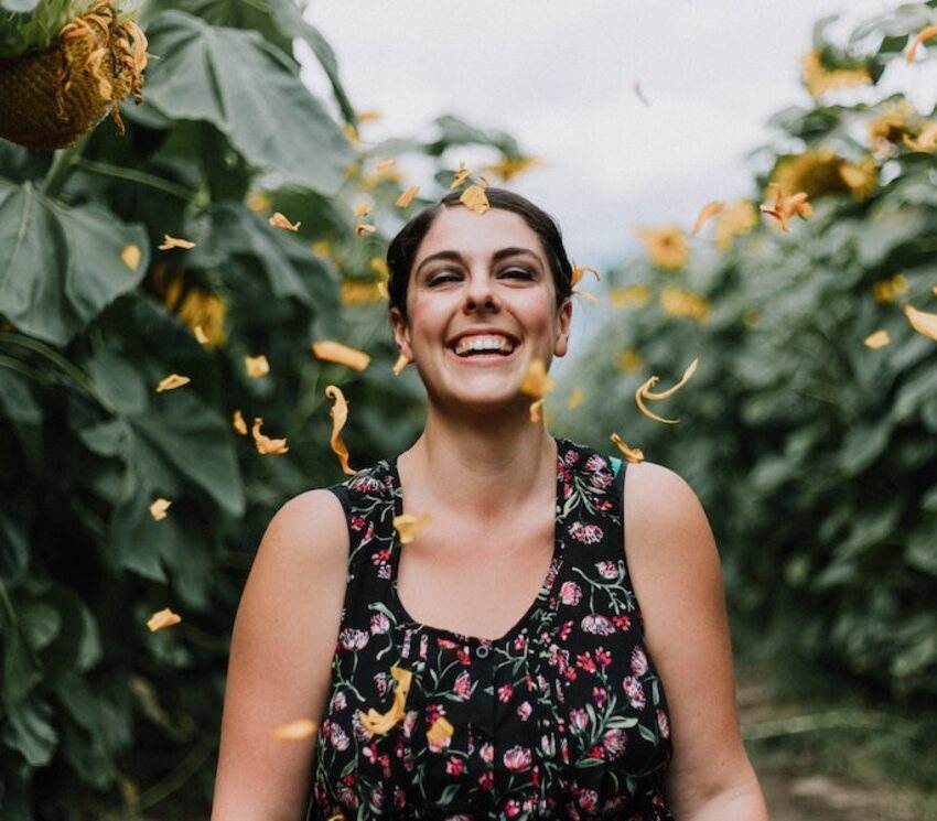 A woman laughing among sunflowers